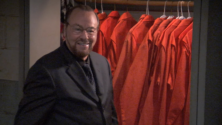 James Lipton as Warden Gentles, smiling in front of a closet of prison jumpsuits on Arrested Development