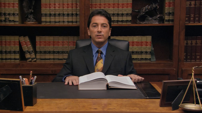 Scott Baio as Bob Loblaw sitting at a desk on Arrested Development