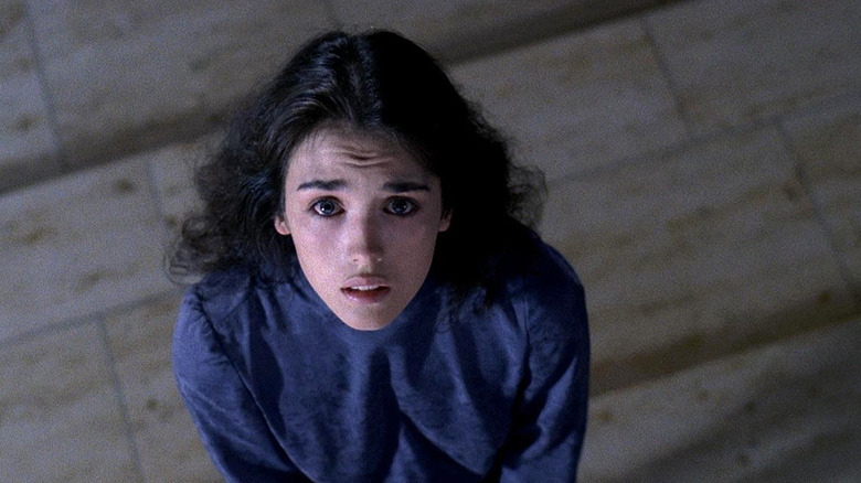 Isabelle Adjani as Anna in Possession, wearing a blue shirt as she looks up past the camera which is angled looking down at her.