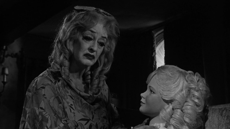 Bette Davis as Baby Jane Hudson mournfully touching a porcelain doll in What Ever Happened to Baby Jane?