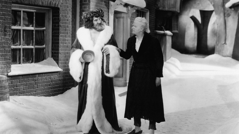 Lionel Braham and Reginald Owen as the Ghost of Christmas Present and Ebenezer Scrooge walking together in A Christmas Carol