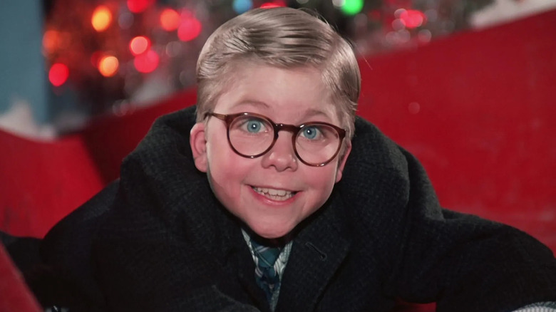 Peter Billingsley as Ralphie Parker, smiling and hanging from a slide in A Christmas Story