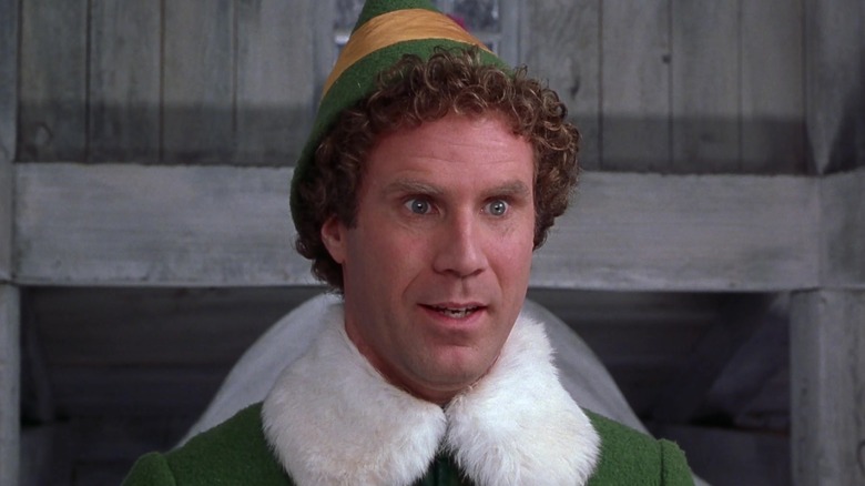 Will Ferrell as Buddy the Elf, smiling in a wooden building in Elf