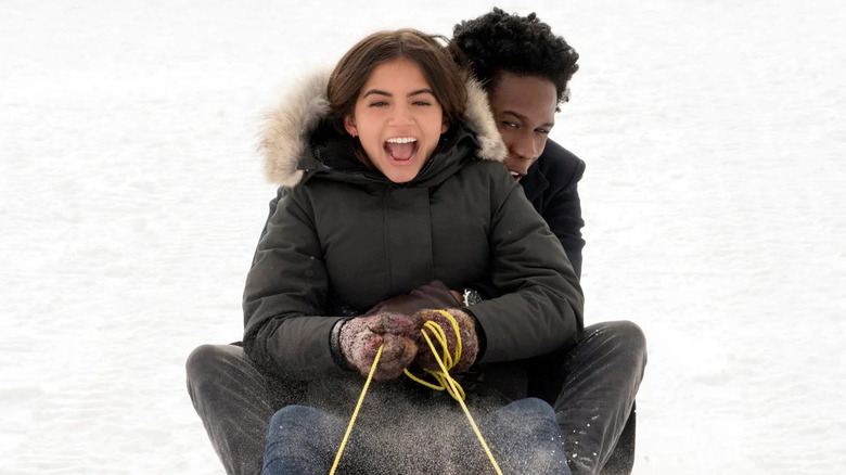 Isabela Merced and Shameik Moore as Julie and Stuart, sharing a sled in Let It Snow