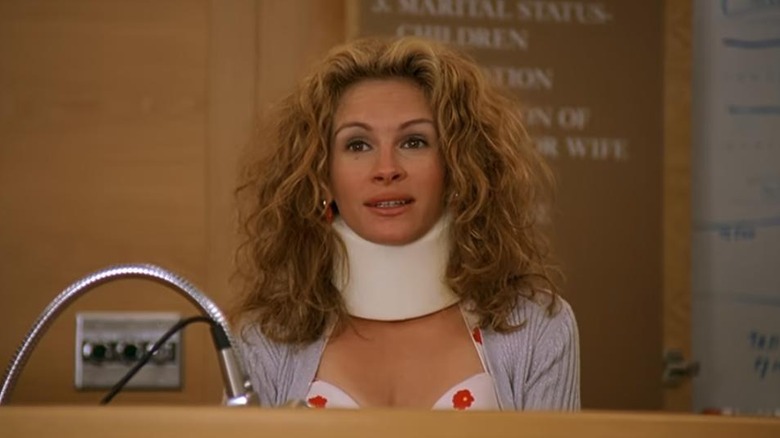 Julia Roberts as Erin Brockovich in Erin Brockovich, sitting at a desk with a neck brace on.