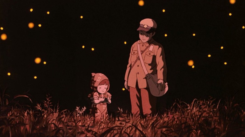 Tsutomu Tatsumi as Seita and Ayano Shiraishi as Setsuko in Grave of the Firelies, the two standing in the dark of a field surrounded by firelies.