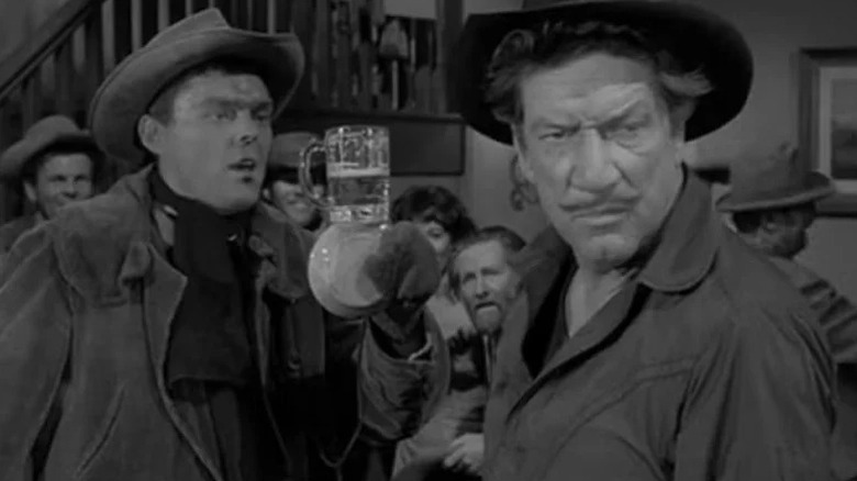 Paladin (Richard Boone) looks away from a man holding a beer in Have Gun - Will Travel
