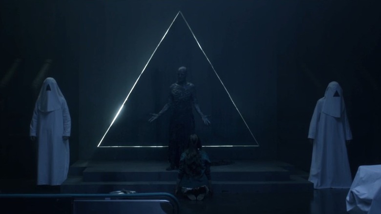 Grace Munro as Maggie kneeling before Kenneth Welsh as Powell, preparing for an incantation in The Void