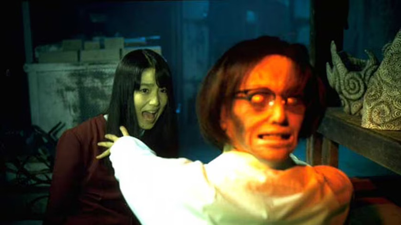 Fhi Fan as Shuichi twisting his head around and freaking out Eriko Hatsune as Kirie, in Uzumaki