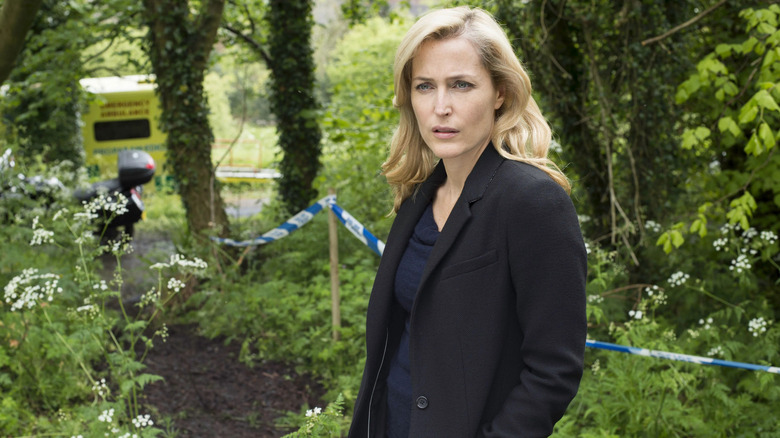 Stella Gibson (Gillian Anderson) stands at a forested crime scene in The Fall