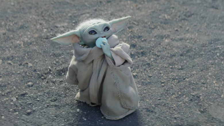 Grogu looking up and eating blue macarons AKA Nevarro Nummies on Nevarro in The Mandalorian and Grogu