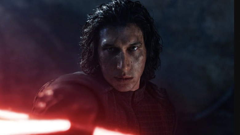 Adam Driver as Ben Solo/Kyloe Ren weilding his red crossguard lightsaber in the snow on Starkiller Base in Star Wars: The Force Awakens