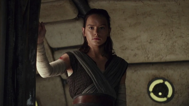 Daisy Ridley as Rey standing in the doorway of the Millennium Falcon looking at Ben at the end of Star Wars: The Last Jedi