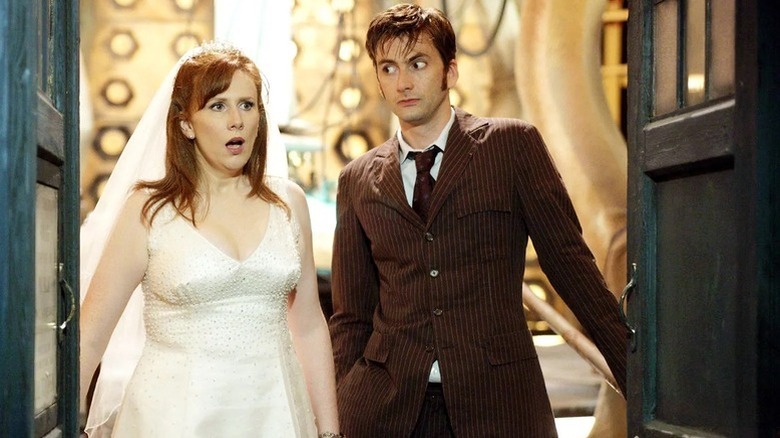 Donna Noble (Catherine Tate) stands in a wedding dress at the TARDIS entrance next to the Tenth Doctor (David Tennant) in Doctor Who