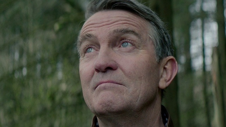 Graham O'Brien (Bradley Walsh) looks stoically upward in a forest in Doctor Who