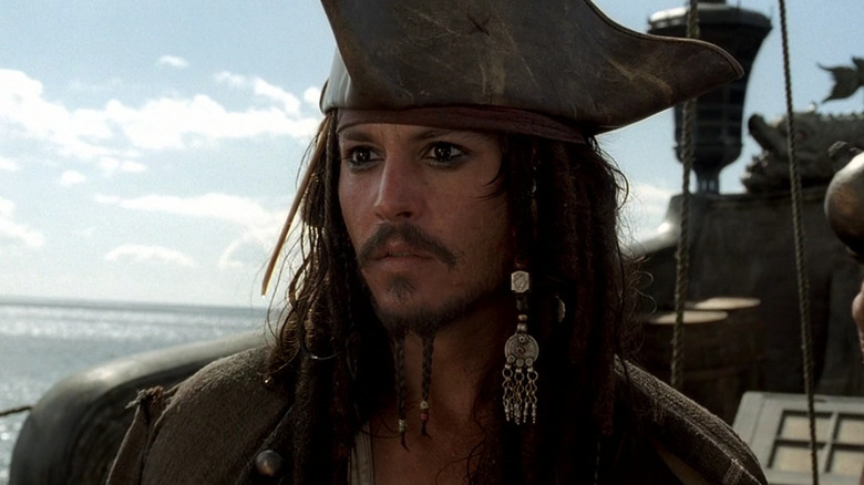 Johnny Depp as Captain Jack Sparrow in Pirates of the Caribbean: The Curse of the Black Pearl, standing on a boat in the sea.