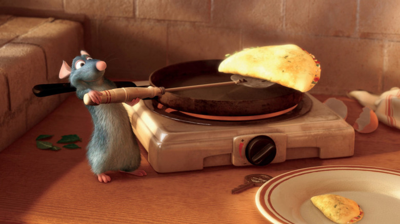 Patton Oswalt as Remy in Ratatoullie, lifting an omelet off of a tiny rat-sized frying pan.