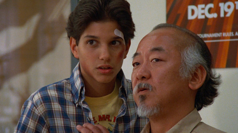 A bruised Daniel LaRusso (Ralph Macchio) stands close to Mister Miyagi (Pat Morita) in The Karate Kid (1984)