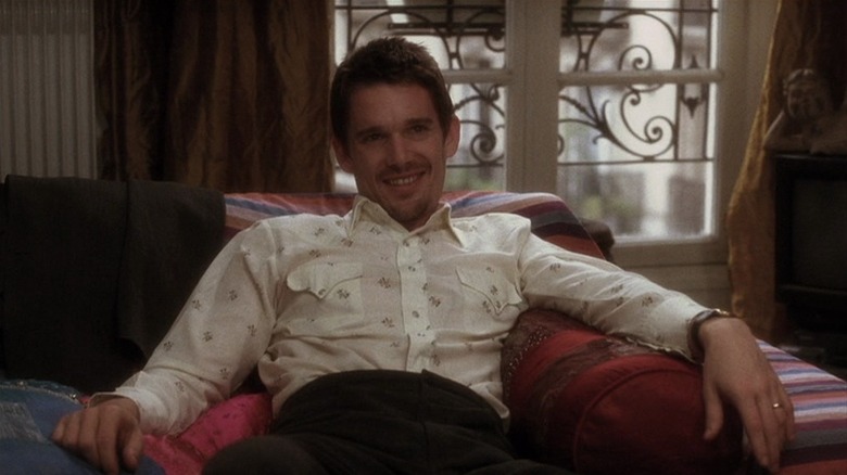 Jesse (Ethan Hawke) grins while sitting in an apartment in Before Sunset