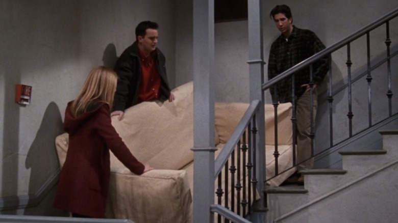 Jennifer Aniston as Rachel Green, Matthew Perry as Chandler Bing, and David Schwimmer as Ross Geller moving a couch inin the Friends episode "The One with the Cop"