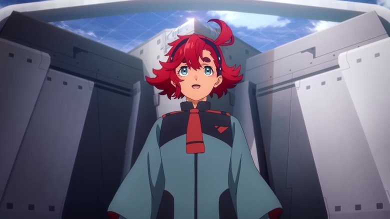 Suletta Mercury looks up happily in front of a metallic building in Mobile Suit Gundam: The Witch from Mercury