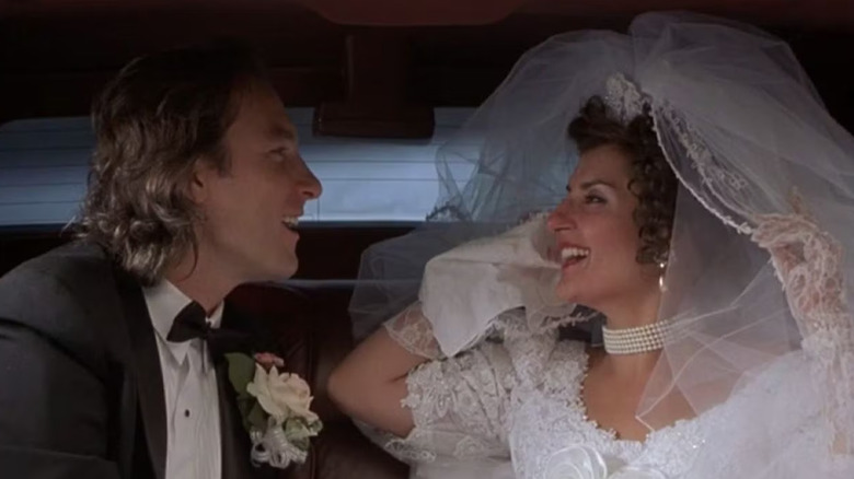 John Corbett and Nia Vardalos laughing together in the back of a limo in My Big Fat Greek Wedding