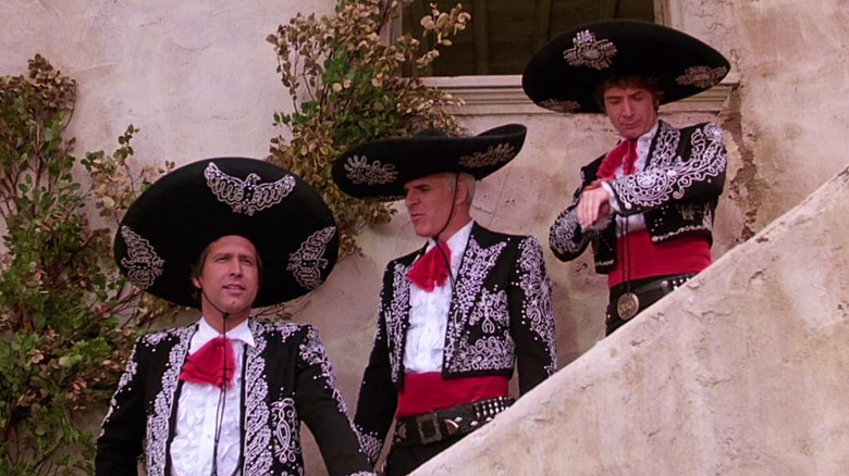Dusty, Lucky, and Ned (Chevy Chase, Steve Martin, and Martin Short) in their Three Amigos costumes on an outside staircase