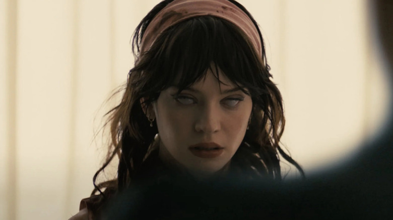 Companion - Sophie Thatcher as Iris with blank eyes over Josh's shoulder at edge of frame