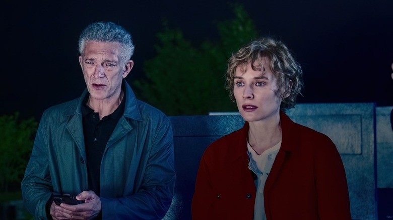 Vincent Cassel as Karsh standing in a graveyard with Diane Kruger as Terry in The Shrouds