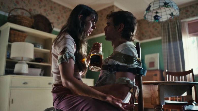 Millie sits on top of Tim, who is taped to a chair in Together