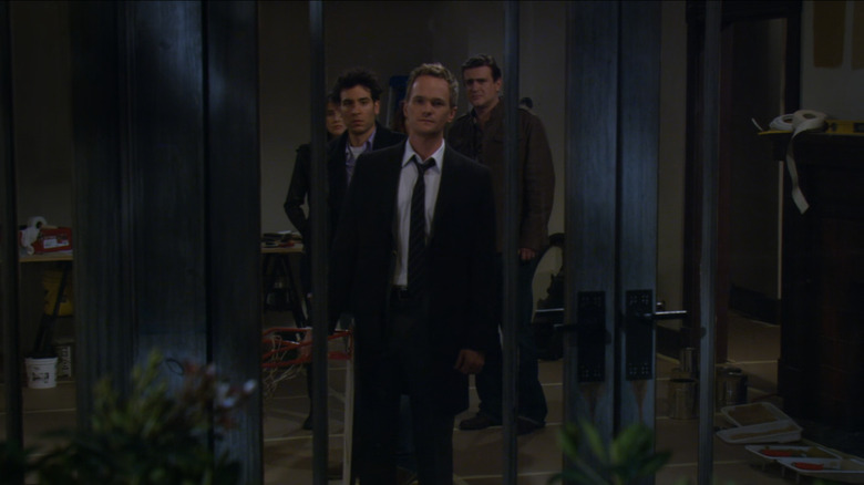 Barney Stinson (Neil Patrick Harris) looks crestfallen out a window while holding a basketball hoop as his friends stand behind him in How I Met Your Mother