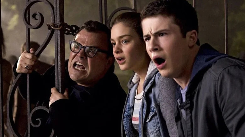 Nathan Lane as R.L. Stine making scary face next to Odeya Rush as Hannah and Dylan Minnette as Zach looking shocked in Goosebumps