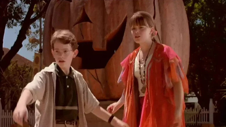 Children Joey Zimmerman as Dylan and Kimberly J. Brown as Marnie standing in front of giant pumpkin in Halloweentown