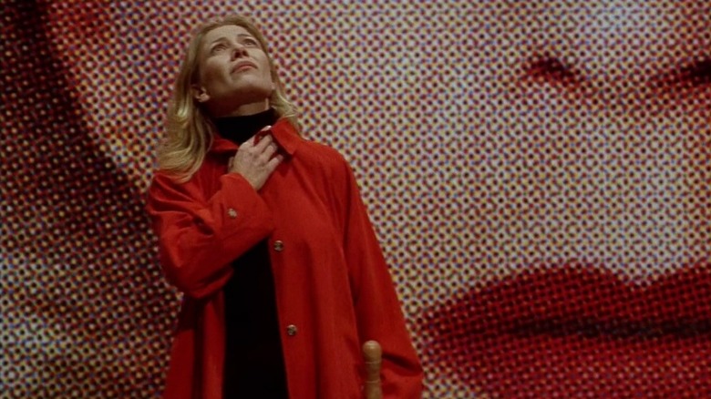 Cecilia Roth as Manuela standing in front of huge image of woman's face in All About My Mother