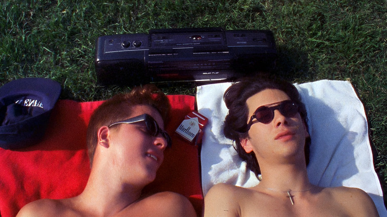 Roko Belic as Tommy and James Duval as Andy lying on towels with sunglasses and boombox in Totally F***ed Up