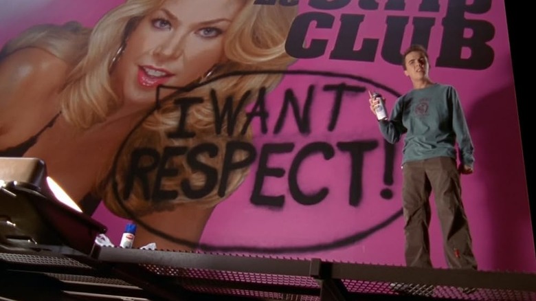 Malcolm (Frankie Muniz) next to graffitied billboard on Malcolm in the Middle