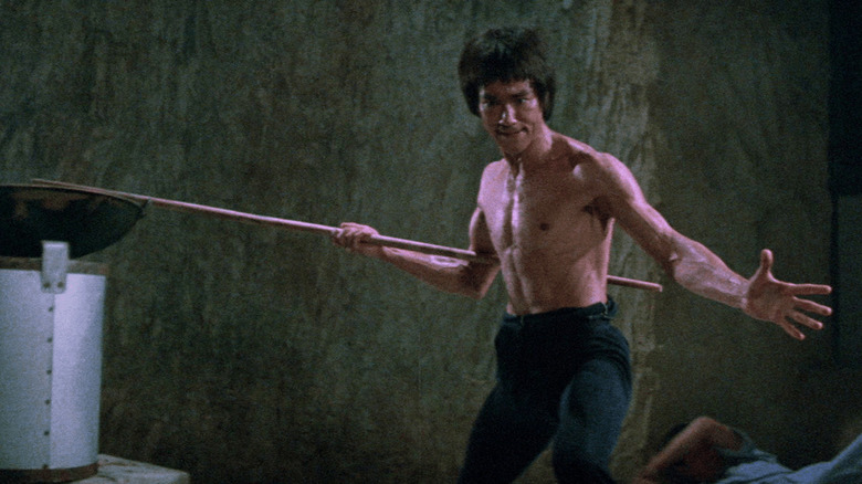 Lee (Bruce Lee) stands with a bo staff ready in Enter the Dragon