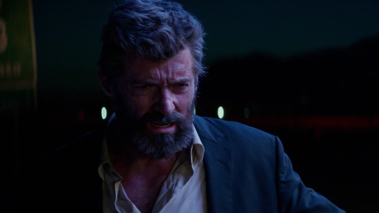 A medium shot of Hugh Jackman as Logan/Wolverine, lit in blue fluorescent light.