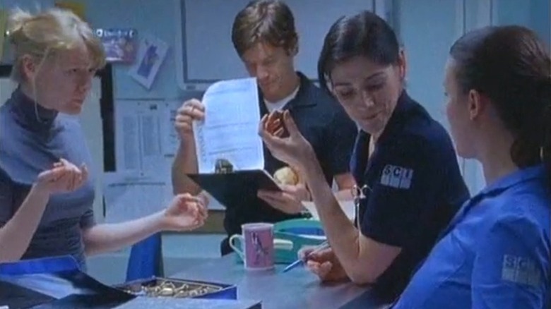 The cast of Bodies standing around a hospital counter