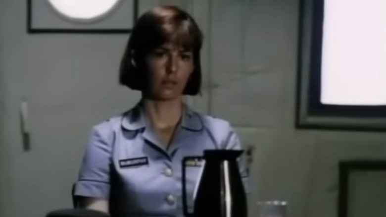 Dana Delany as Colleen McMurphy sitting behind a desk on China Beach
