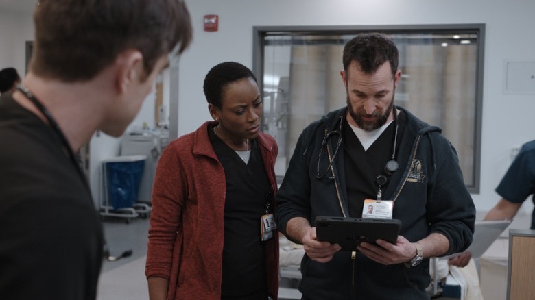 Tracy Ifeachor as Dr. Heather Collins and Noah Wyle as Dr. Michael "Robby" Robinavitch looking at a tablet on The Pitt