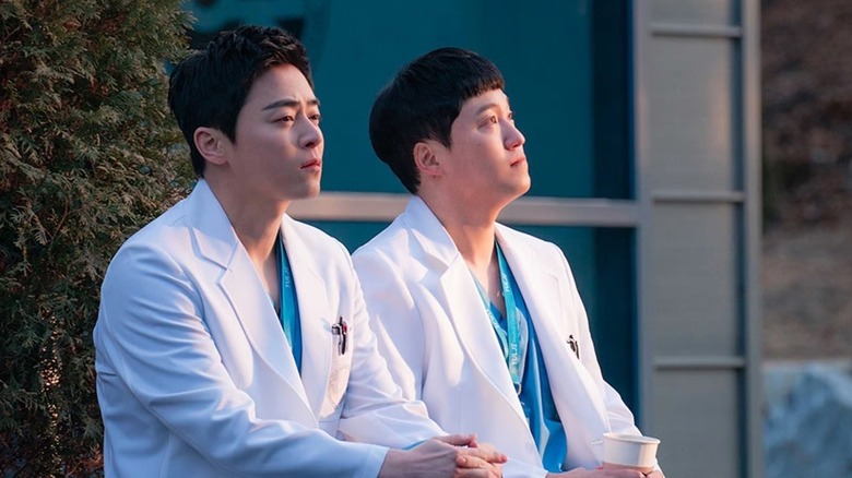 Lee Ik-jun (Jo Jung-suk) and Yang Seok-hyeong (Kim Dae-myung) sit outside at sunrise in Hospital Playlist