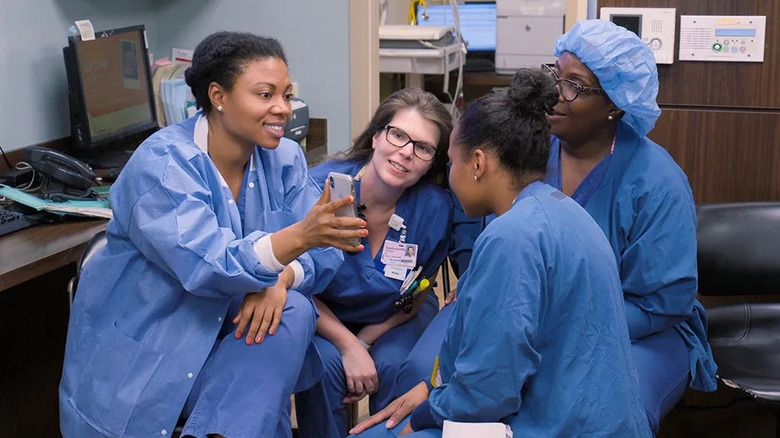 The medical staff at Lenox Hill sit and look at an iPhone in Lenox Hill