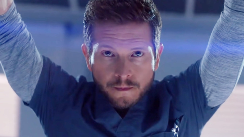 Conrad Hawkins (Matt Czuchry) stands with his arms raised in The Resident