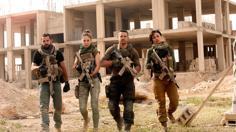 Sergeant Samuel Wyatt (Daniel MacPherson), Captain Natalie Reynolds (Roxanne McKee), Sergeant Thomas 'Mac' McAllister (Warren Brown), and LCpl. Gracie Novin (Alin Sumarwata) approach with guns in Strike Back.