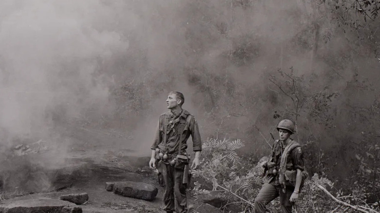 Two soldiers stand in a smoky jungle in The Vietnam War