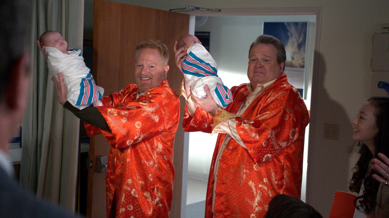 Jesse Tyler Fergusson and Eric Stonestreet as Mitchell and Cam holding babies on Modern Family