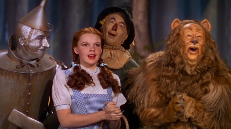 The Tin Man, Judy Garland as Dorothy, the Scarecrow, and the Lion, lined up in The Wizard of Oz