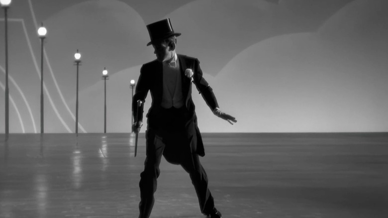 Fred Astaire as Jerry, in silhouette showing off his top hat and cane, onstage in Top Hat