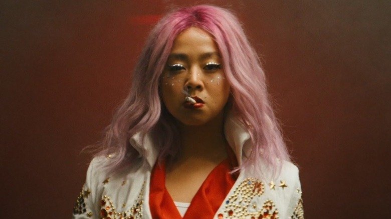 Stephanie Hsu as Jobu Tupacki in Everything Everywhere All At Once, sporting pink hair, a bejewled jacket, and smoking a cigarette.